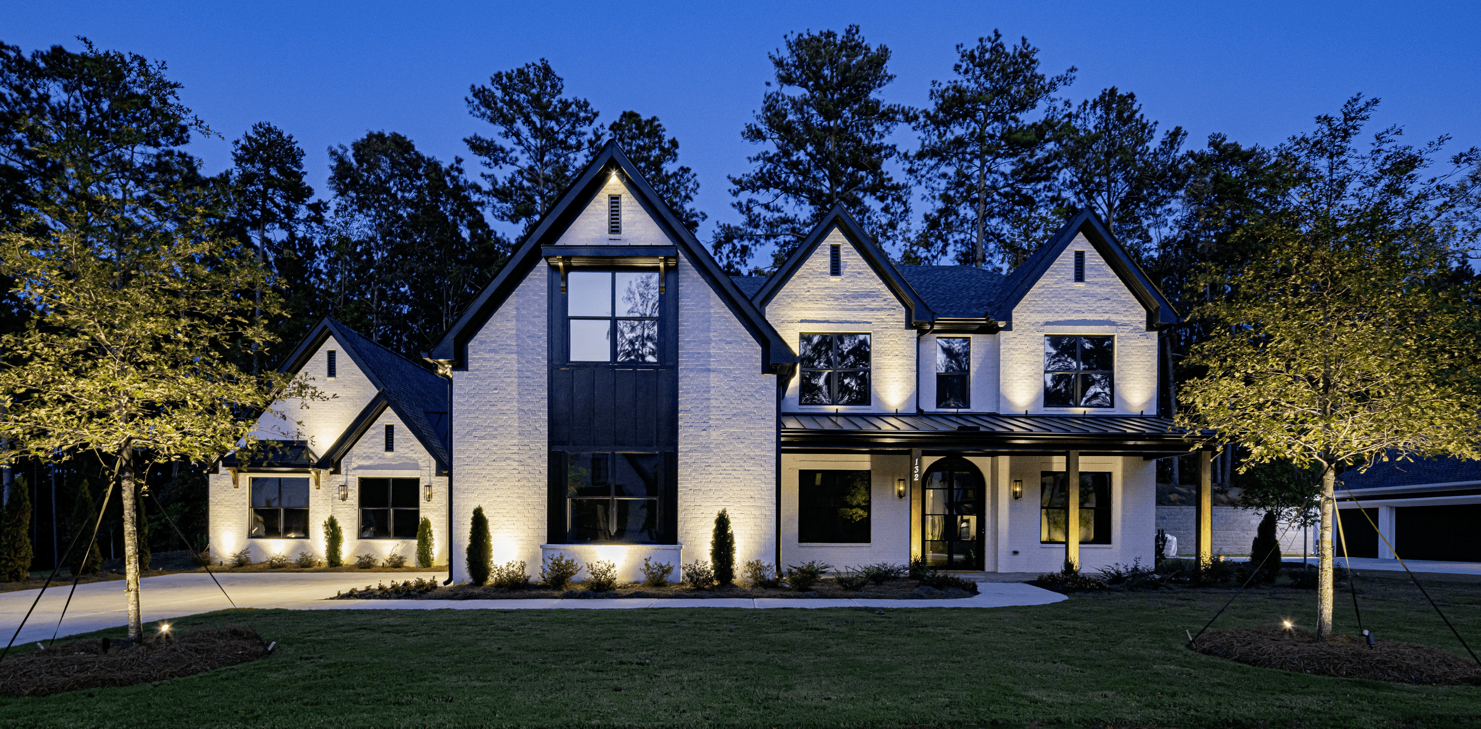 A flagship landscape lighting project at dusk, layered architectural and tree lighting across a distinguished home