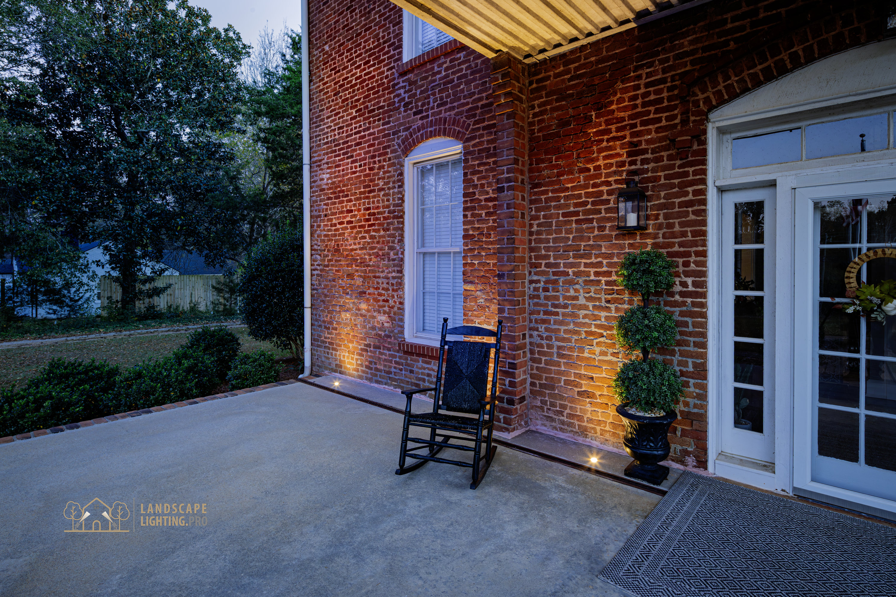 Detail of the 1850 home's lit columns and brick at dusk