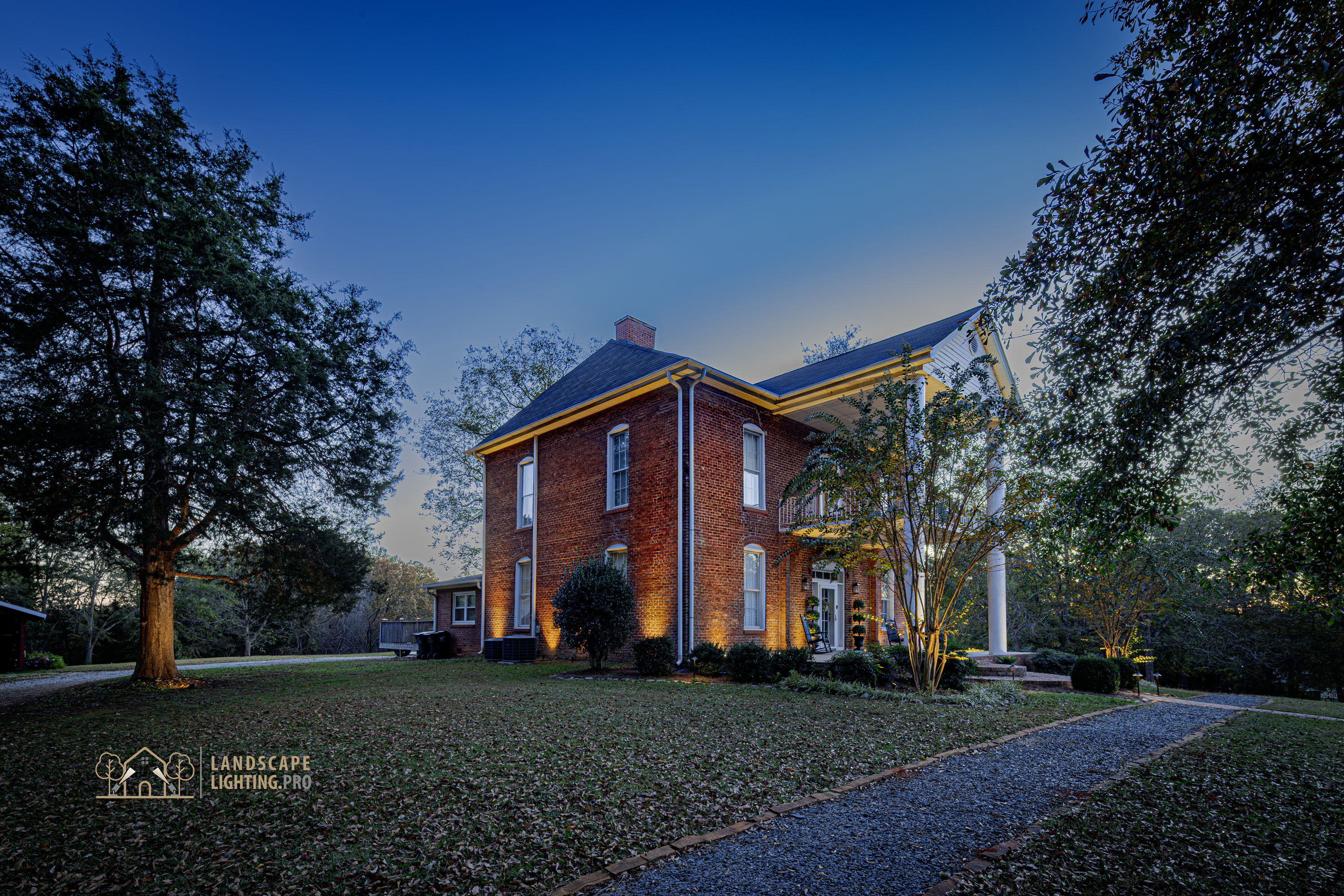 An 1850 brick home illuminated at dusk, with warm light revealing the columns and façade detail