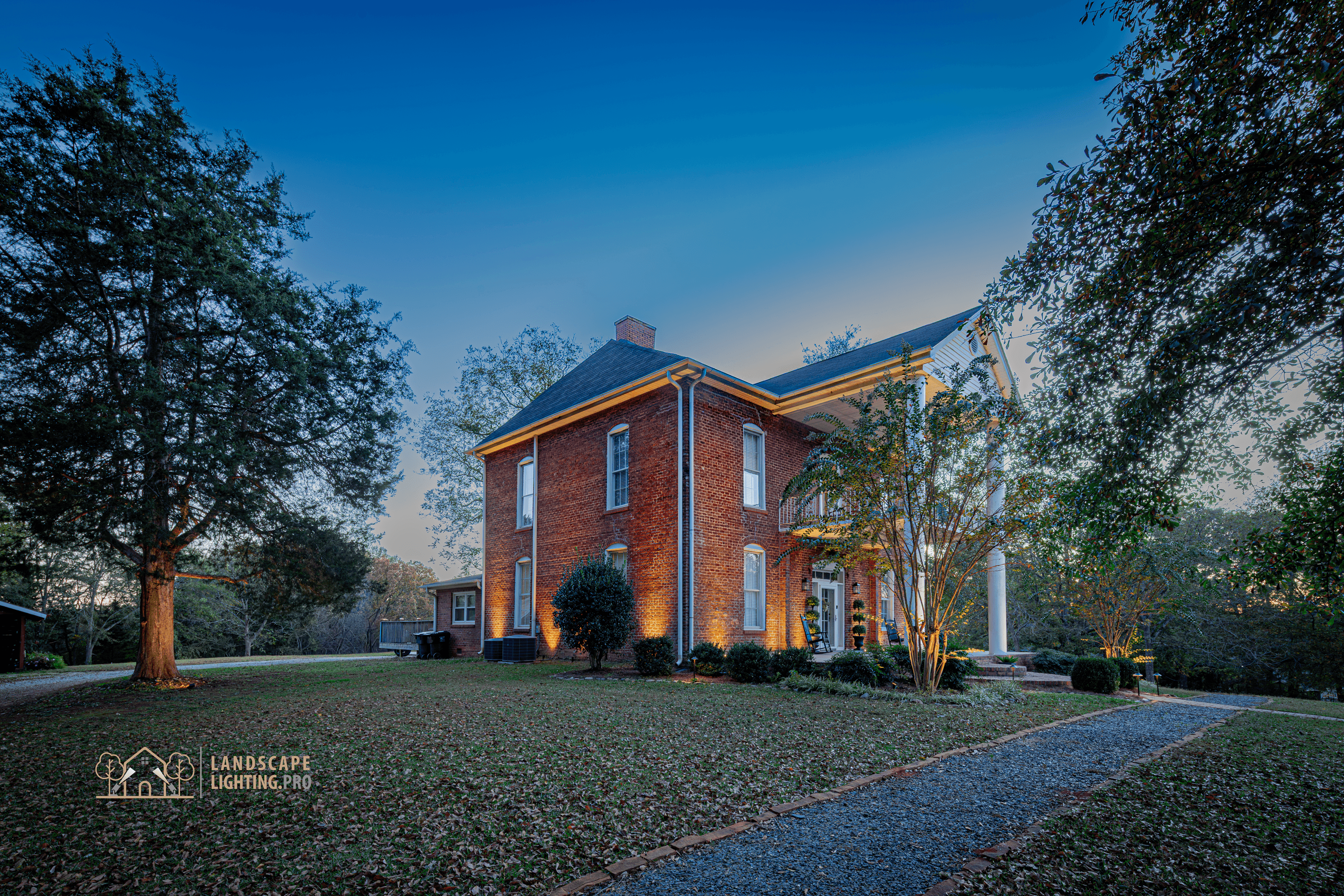 An 1850 brick home illuminated at dusk, with warm light revealing the columns and façade detail