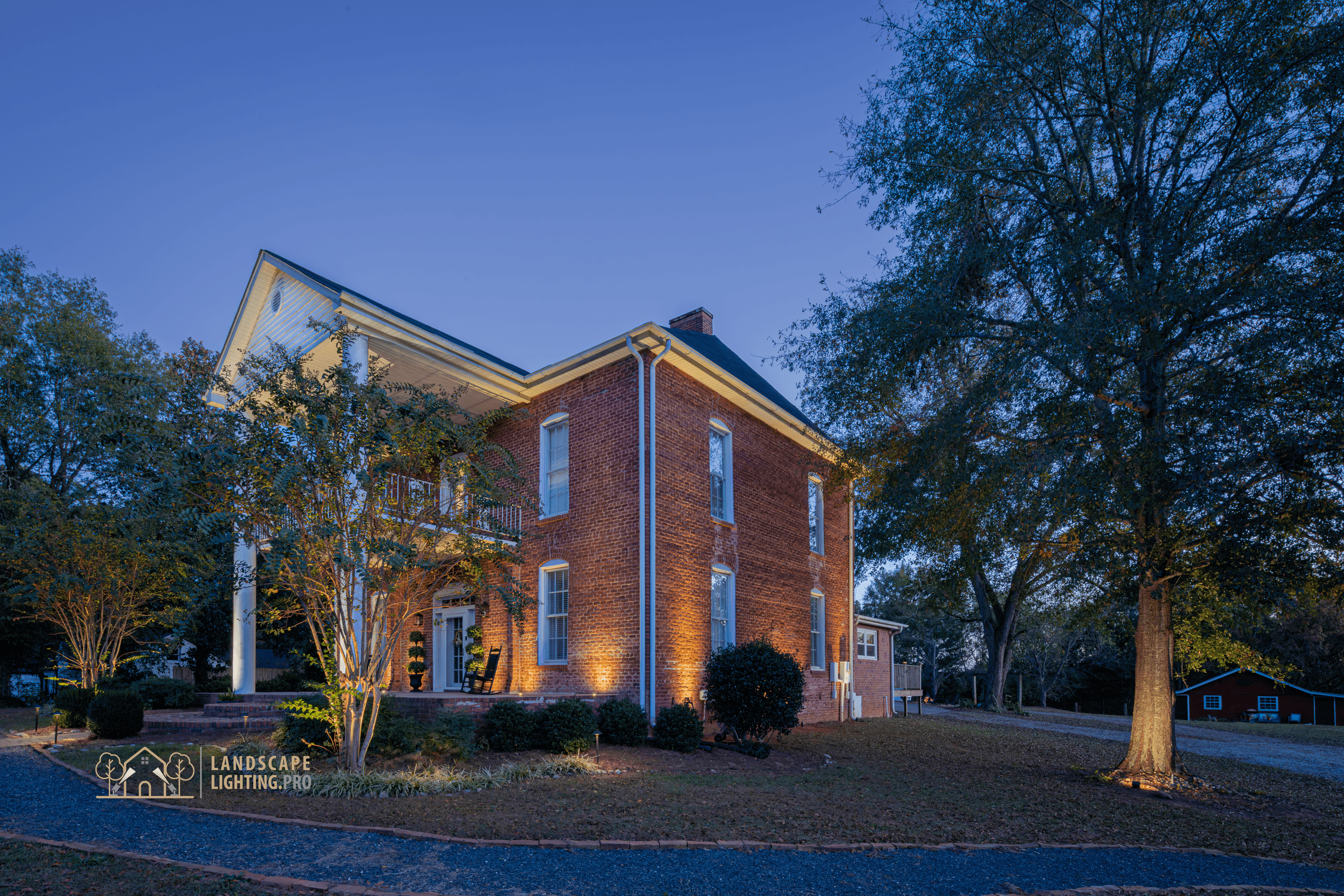 A side view of the historic home and lit landscape at dusk