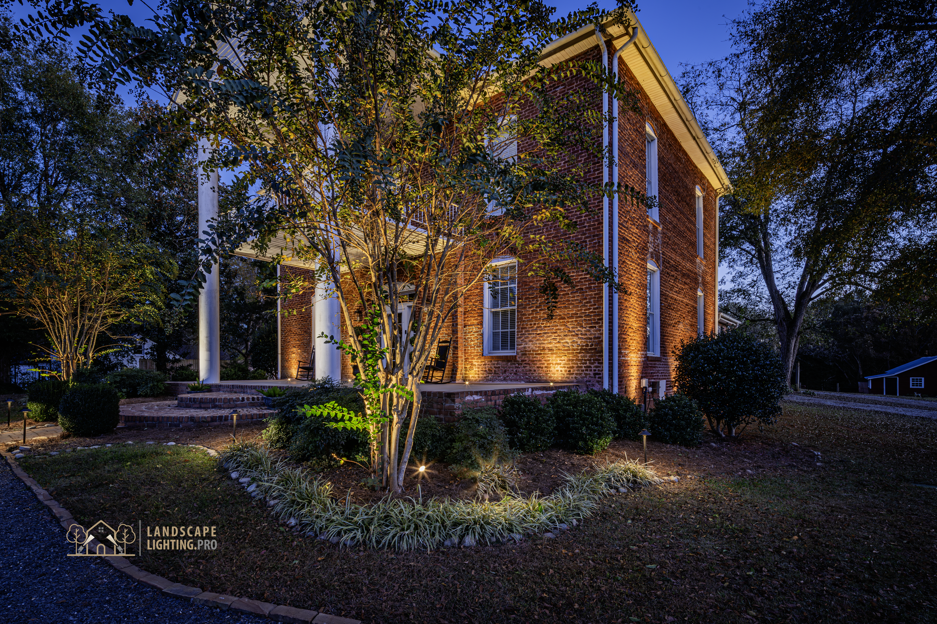 The 1850 home's brick façade illuminated, with columns and frieze in detail