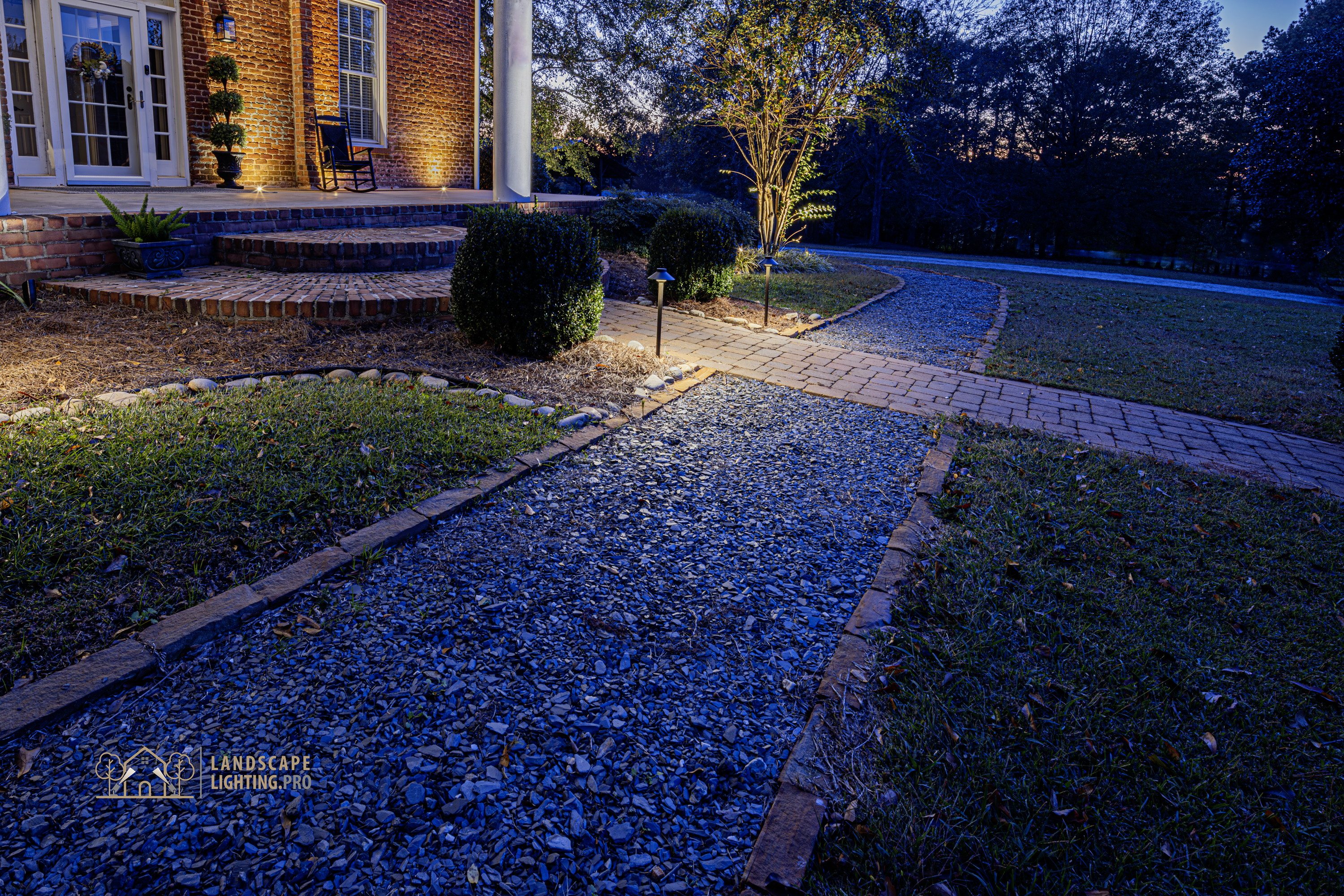 The lit brick walkway leading to the historic home's entrance