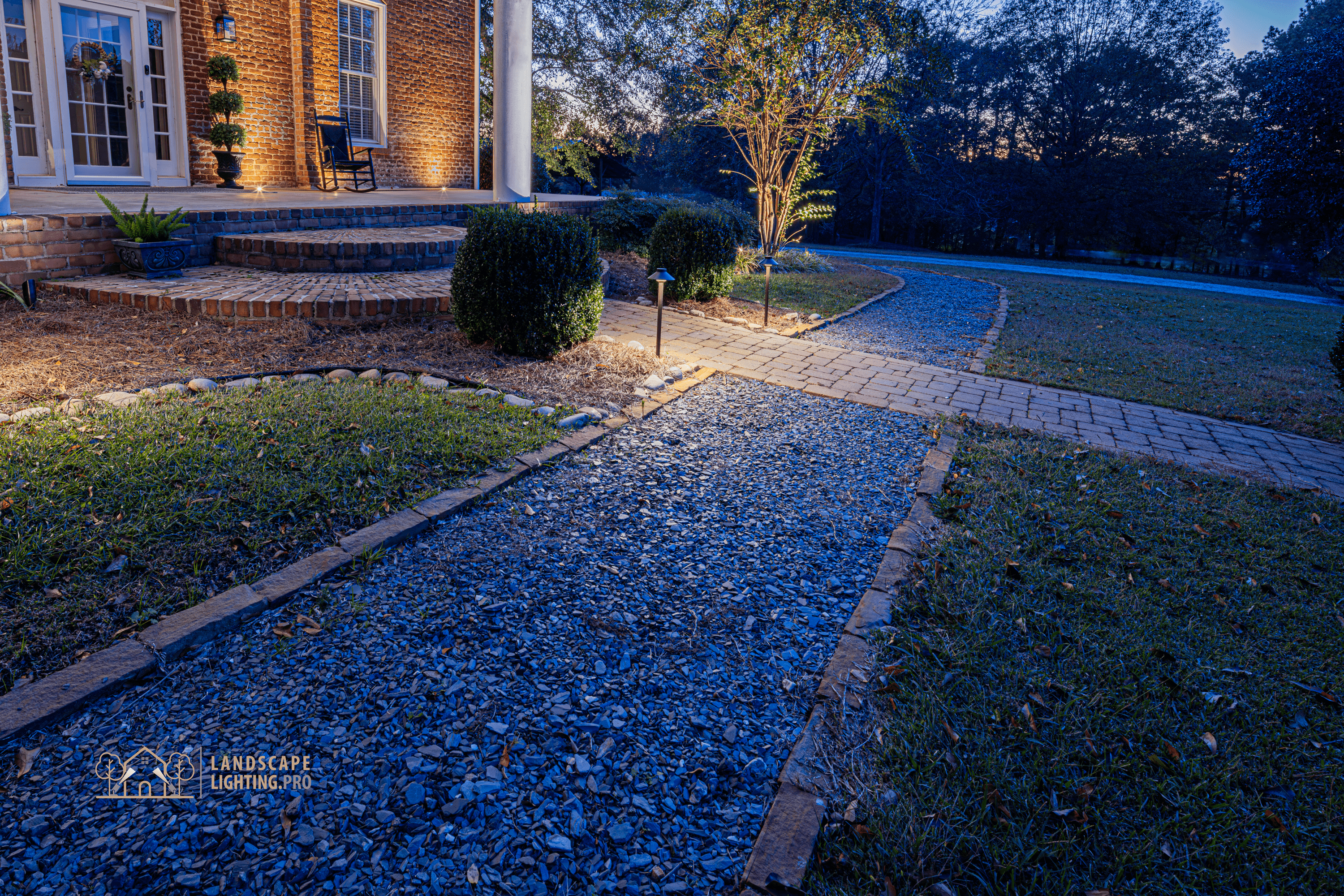 The lit brick walkway leading to the historic home's entrance