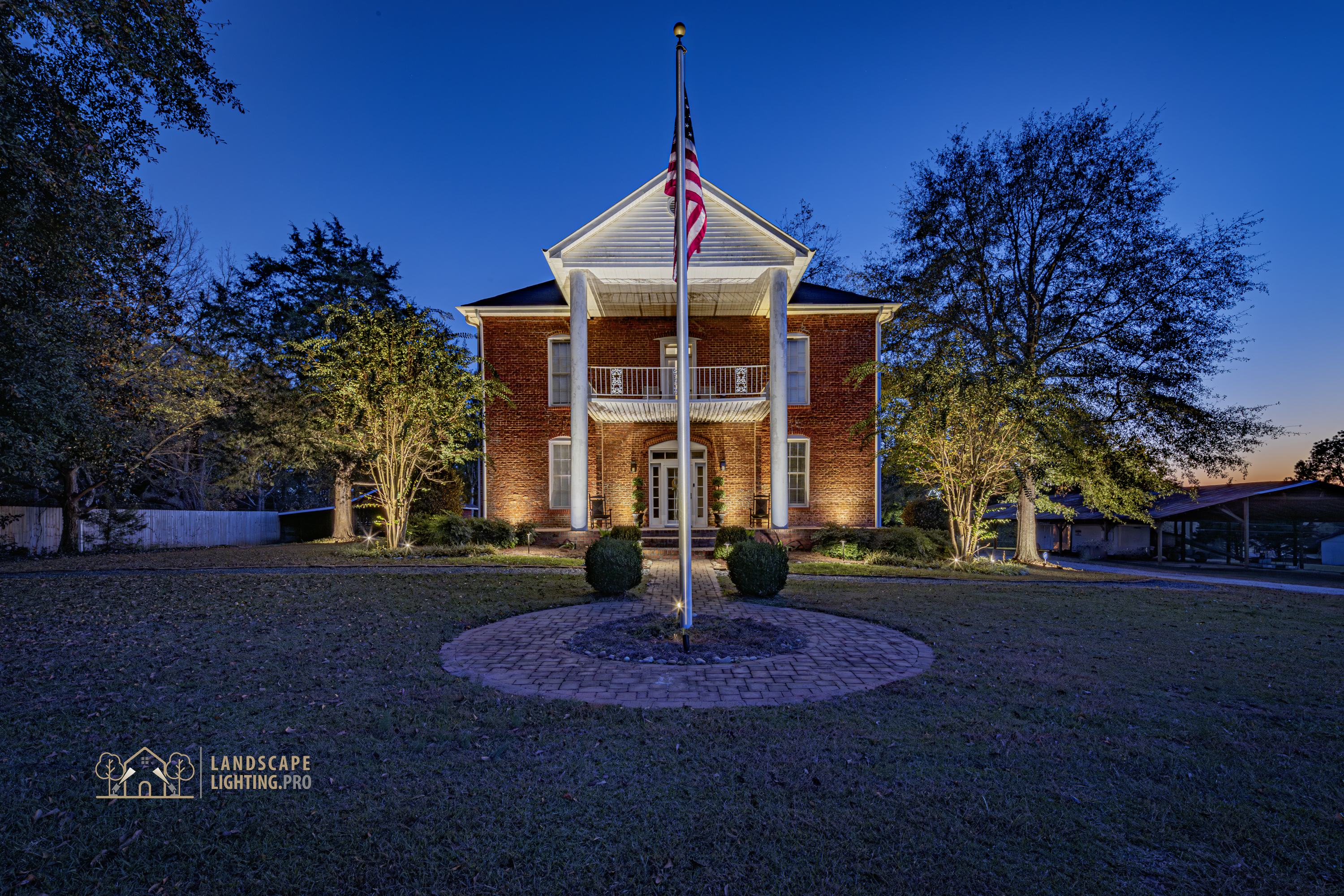 A wide view of the 1850 home and grounds illuminated at dusk