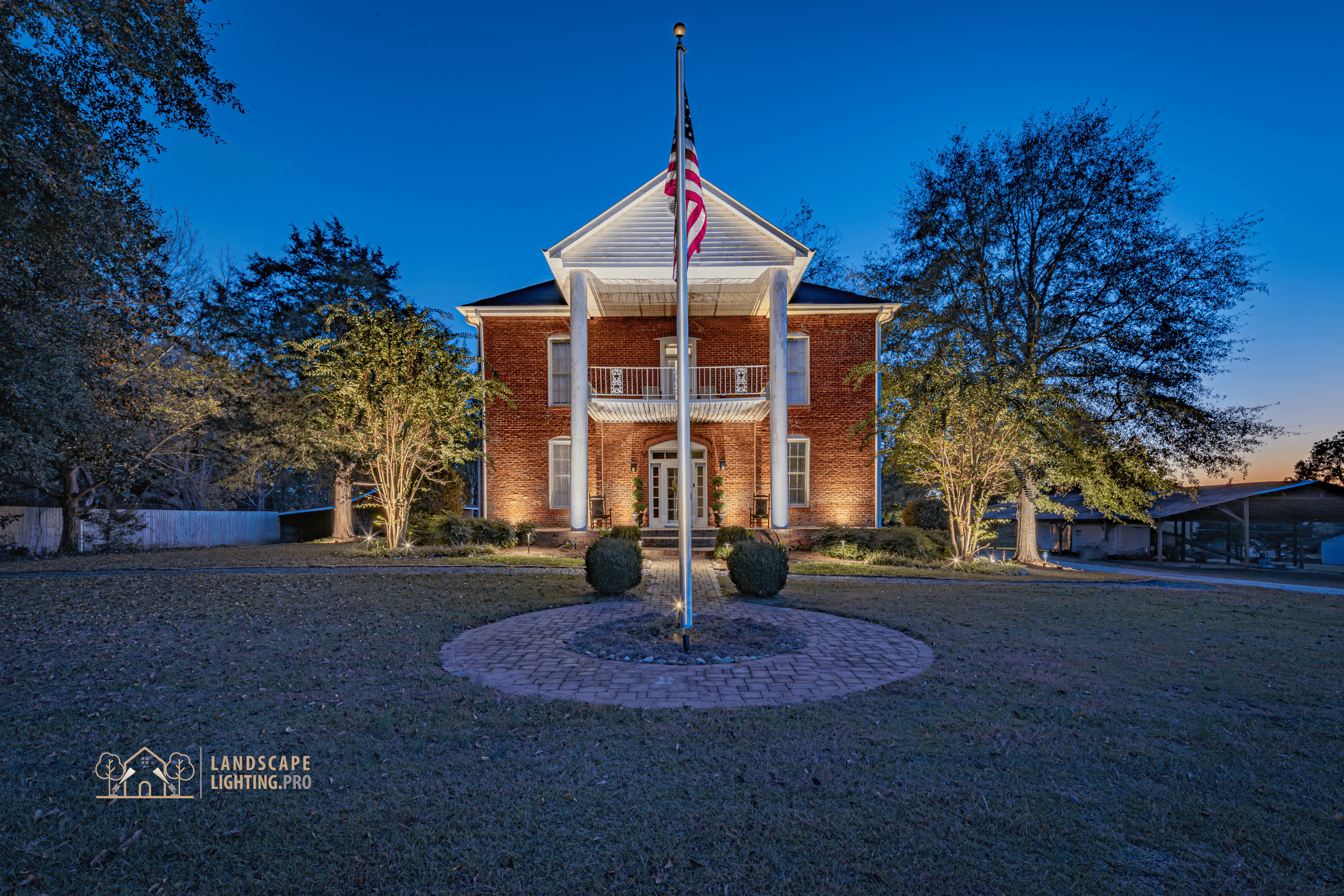 A wide view of the 1850 home and grounds illuminated at dusk
