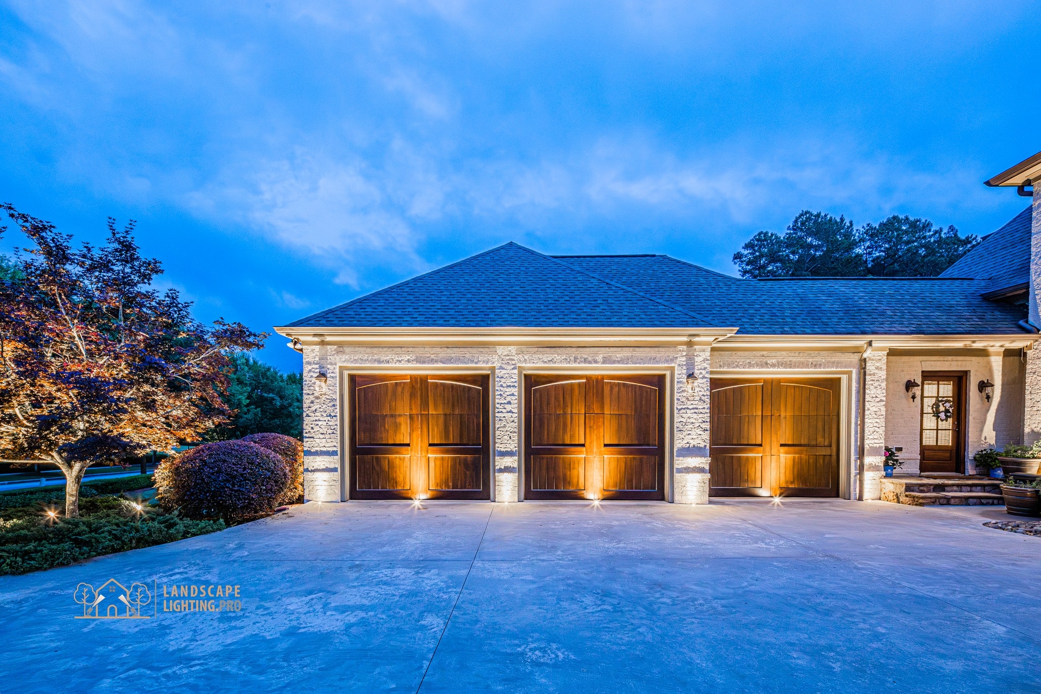 Close detail of three garage doors with copper trim, lit cleanly at dusk on the estate